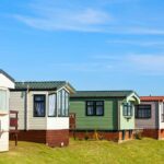 Row of colorful mobile homes on a grassy hill under a blue sky