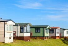 Row of colorful mobile homes on a grassy hill under a blue sky