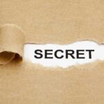 Governor’s Family Firm EXPOSED — Billions Missing A torn piece of brown paper revealing the word SECRET underneath