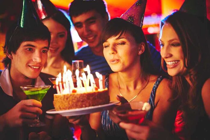 shutterstock_220545766 Group of friends celebrating a birthday with a cake and drinks