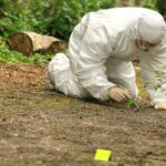 Murder Mystery — 30-Year Search Reignites! Forensic investigator in a protective suit collecting evidence from the ground