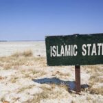 Dems APPROVE 400-Acre Islamic City Plans – Outrage Erupts! A weathered sign reading 'ISLAMIC STATE' in a barren landscape
