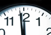 Close-up of a clock showing the time just before noon