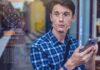 Disneyland SCANDAL: Secret Face Scans EXPOSED! Young man using a smartphone with face recognition overlay