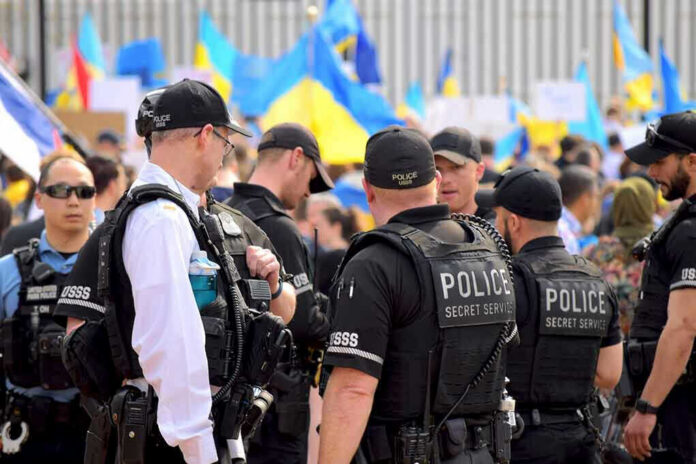 2132863557-1 Police officers gathered near a crowd with flags.