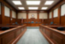 Five Years Loom Over Bolton’s Blunder Empty courthouse courtroom with wooden benches and chairs.