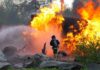 War Jet Crash Sparks Wildfire Firefighter battling a large fire with water spray