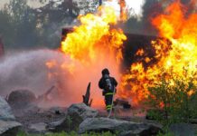 War Jet Crash Sparks Wildfire Firefighter battling a large fire with water spray