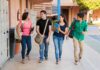 Four students walking together in a school corridor, smiling and chatting