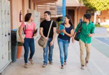 Four students walking together in a school corridor, smiling and chatting