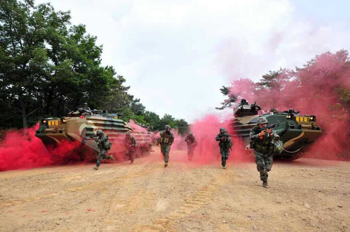 Soldiers running from armored vehicles with red smoke.