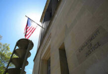 Clearance Rules Bent—Trust Shaken At FBI American flag at Department of Justice building exterior.