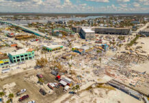 Firefighters Ambushed — Who Hid The Stockpile? Aerial view of hurricane-damaged buildings and debris.