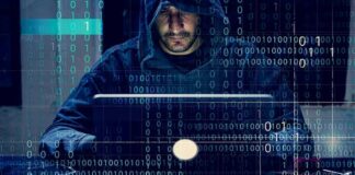 Person in hoodie using a laptop with binary code overlay