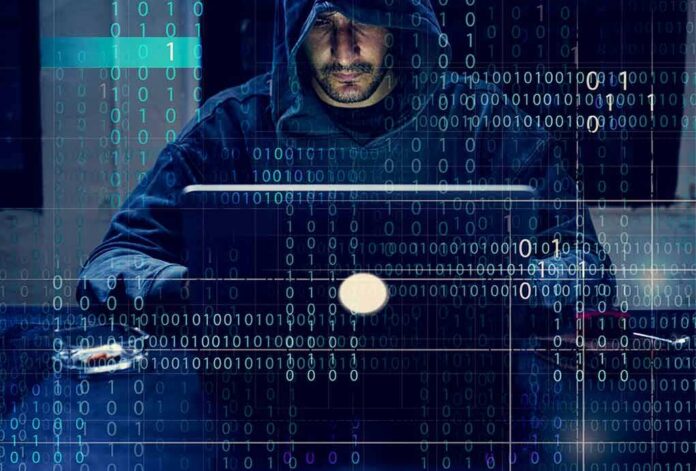 Person in hoodie using a laptop with binary code overlay