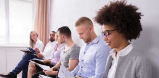 Group of job applicants sitting in a row reviewing documents