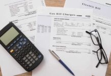 Debt Bomb Defused—or Currency Doom? Utility bills with calculator, pen, and eyeglasses on a desk