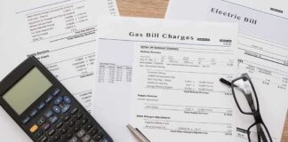 Utility bills with calculator, pen, and eyeglasses on a desk