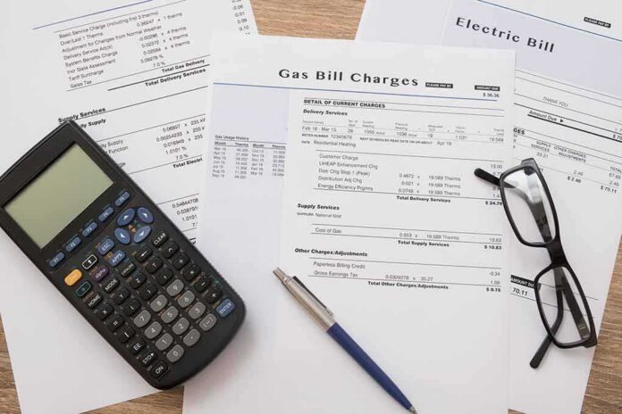 shutterstock_523849567 Utility bills with calculator, pen, and eyeglasses on a desk