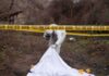 forensic investigator at outdoor crime scene behind caution tape