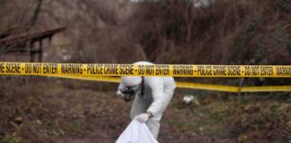forensic investigator at outdoor crime scene behind caution tape