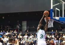 Basketball player dunks the ball in a crowded arena
