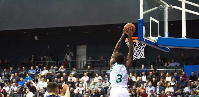 shutterstock_1126537859 Basketball player dunks the ball in a crowded arena