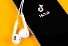 Legal Loophole Rescues TikTok Smartphone with TikTok app and white wired earbuds on yellow background
