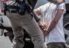 police officer handcuffing a person beside a vehicle