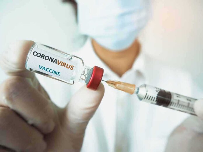 shutterstock_1716721690-1 Healthcare worker holds a COVID-19 vaccine vial and syringe