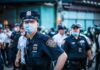 Police officer in mask among colleagues at a city street gathering