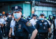 Recall Showdown: Seattle Mayor On The Line Police officer in mask among colleagues at a city street gathering