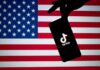 Smartphone with TikTok logo held against a US flag backdrop