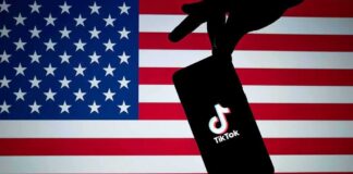 Smartphone with TikTok logo held against a US flag backdrop
