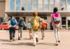 Group of schoolchildren with backpacks running toward a school entrance