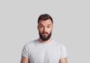 Man with beard making surprised face against gray background