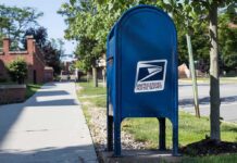 Blue USPS mailbox on a suburban sidewalk