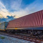 15-Day Land BYPASS: IRAN’S ‘BACK DOOR’ Revealed Freight train with shipping containers on tracks at sunset