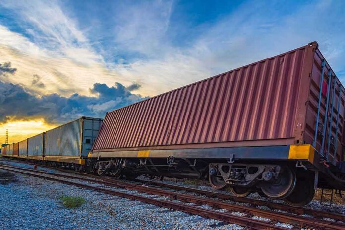 shutterstock_1205372872 Freight train with shipping containers on tracks at sunset