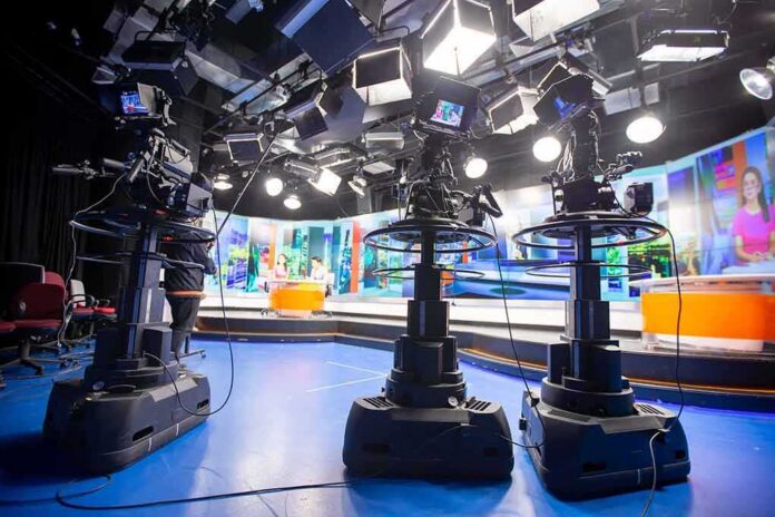 shutterstock_1212918049 television studio with cameras on pedestals facing news desk