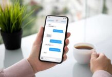 Person holding smartphone with messaging app beside a cup of coffee