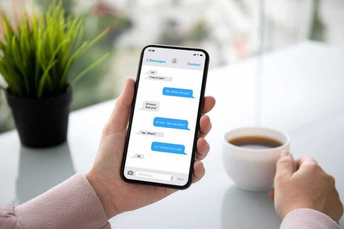 shutterstock_1232266612 Person holding smartphone with messaging app beside a cup of coffee