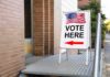 Congress Bails – High-Stakes Fights Frozen Sidewalk sign with American flag directing to a polling place