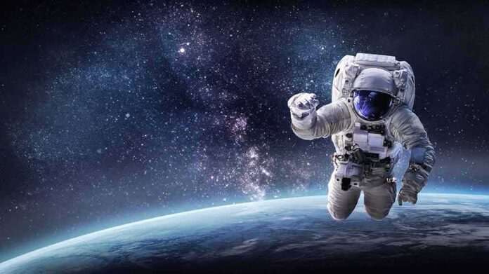 shutterstock_1389007775 Astronaut floating above Earth against a starry galaxy backdrop