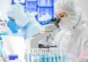 CEO Arrests Jolt Federal Forensics Purchases Scientist in protective suit using a microscope