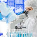 CEO Arrests Jolt Federal Forensics Purchases Scientist in protective suit using a microscope