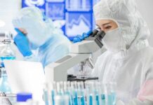 Scientist in protective suit using a microscope