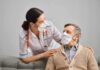 nurse with stethoscope comforting elderly man wearing masks