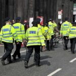 Andrew’s Dark Secrets: New Police PROBE Police officers in high-visibility jackets walking on a city street