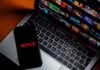 Smartphone with Netflix logo on a laptop keyboard